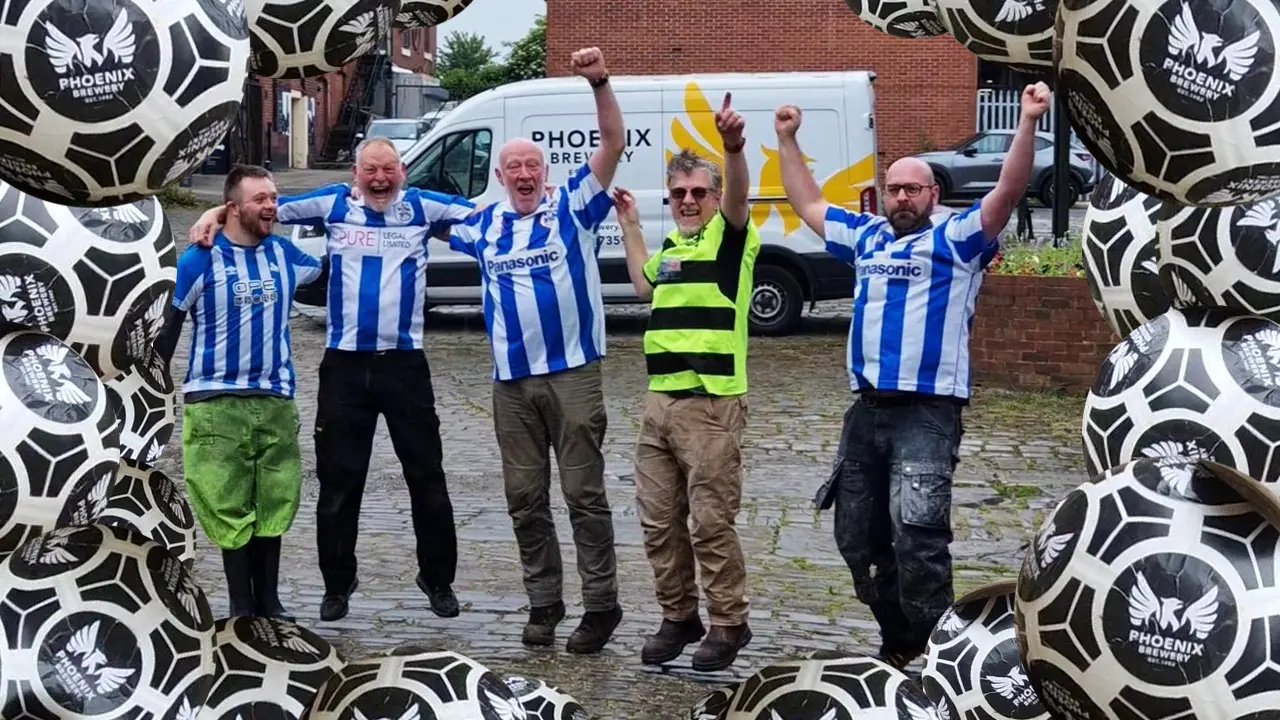 Some of the members of Team Phoenix wearing blue and white football shirts celebrating with their arms raised in front of a Phoenix Brewery van. Multiple footballs with the Phoenix Brewery logo frame the image.