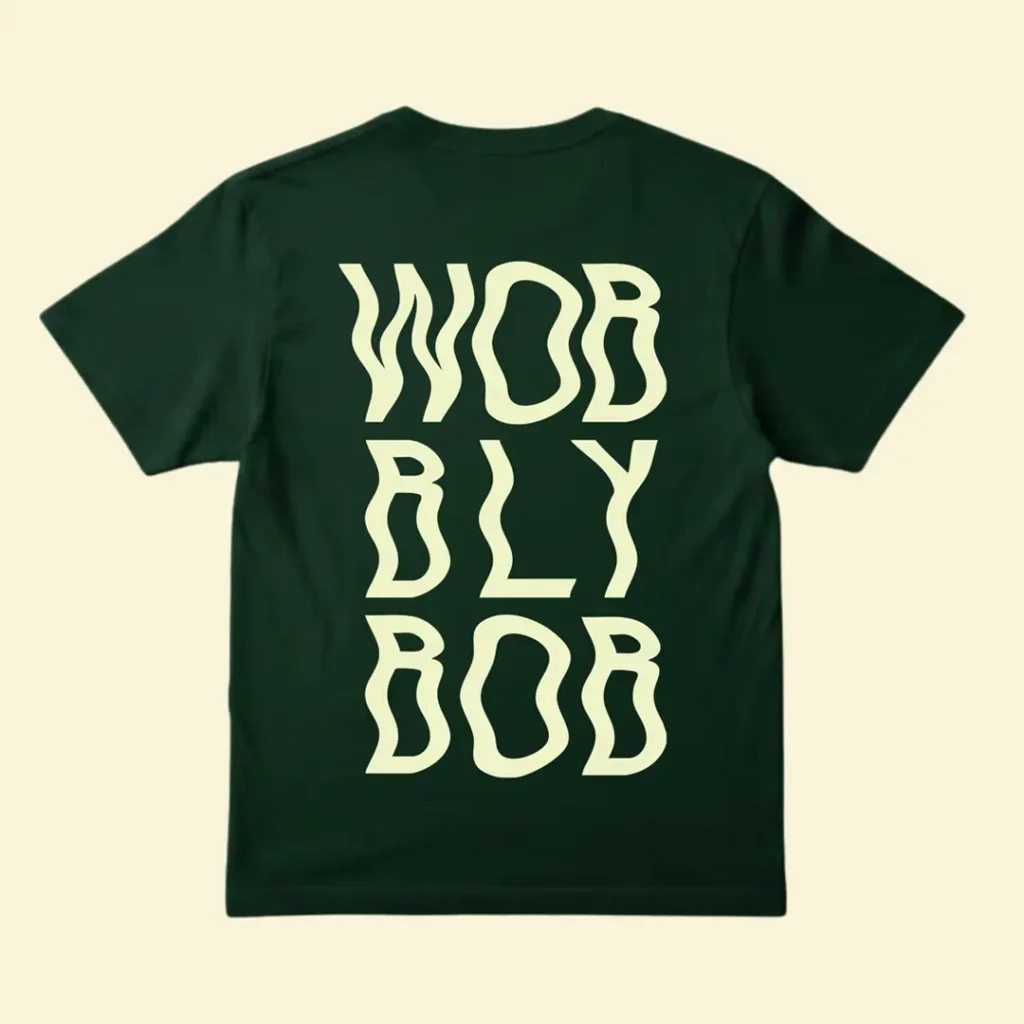 Dark green t-shirt back print with large cream wavy "WOBBLY BOB" stacked text on a cream background